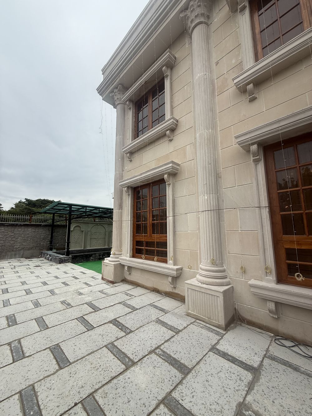Stone-clad wall with carved window surrounds and a fluted column, Hyderabad residence